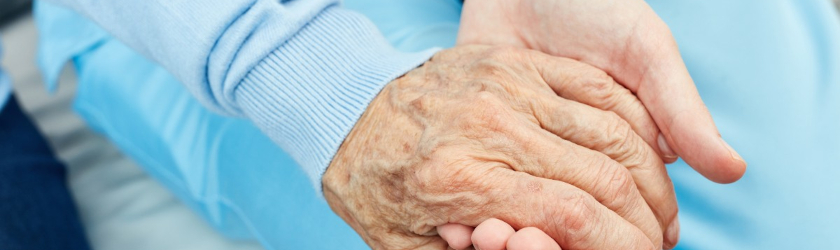 Elderly person's hand being held by a young woman