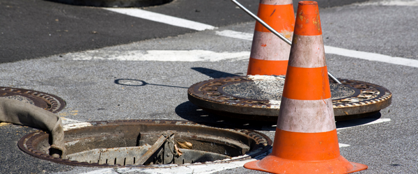 Manhole cover pushed off entrance to sewer in New Jersey with two safety cones around it